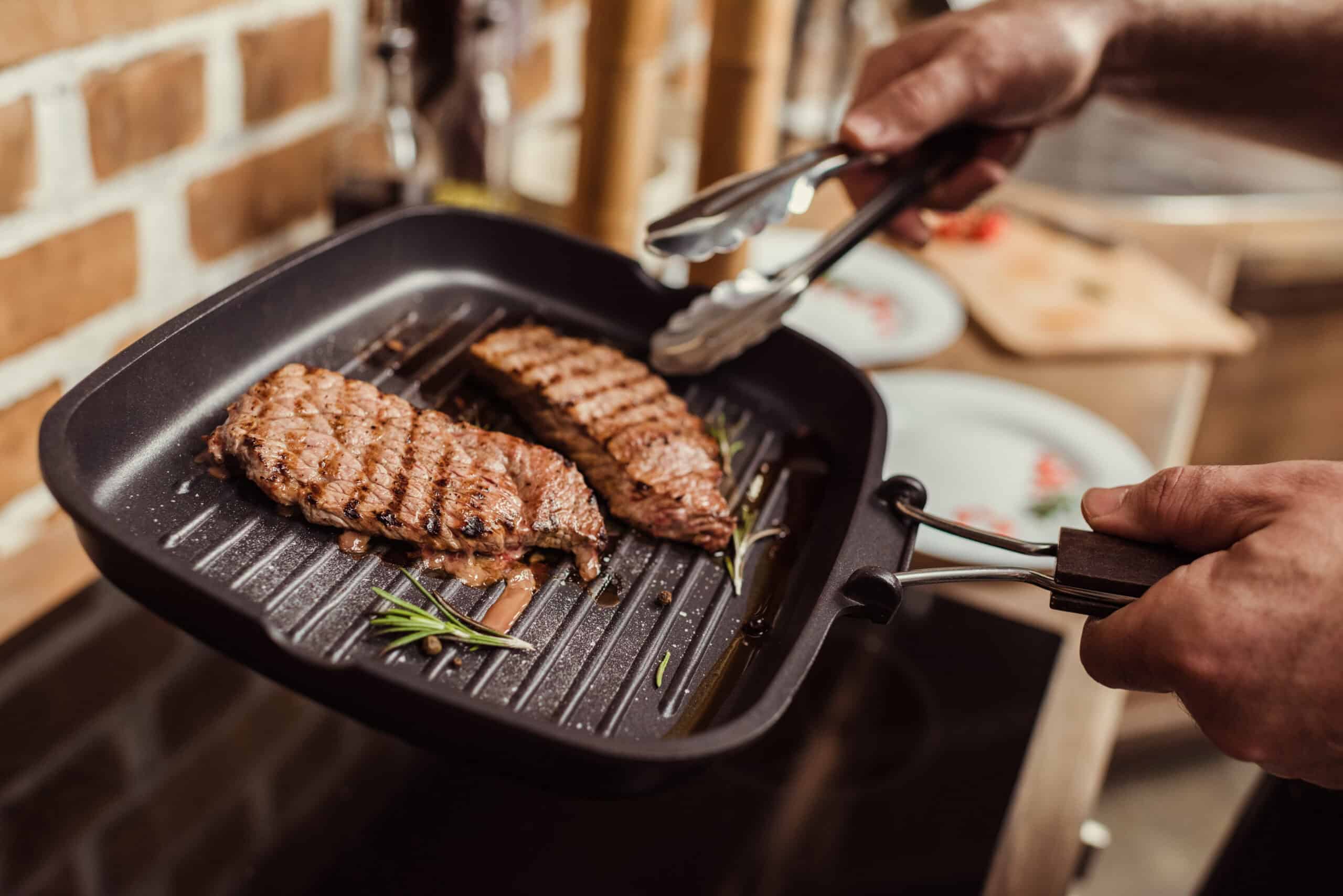 Sirloin steak pieces searing in a hot frying pan
